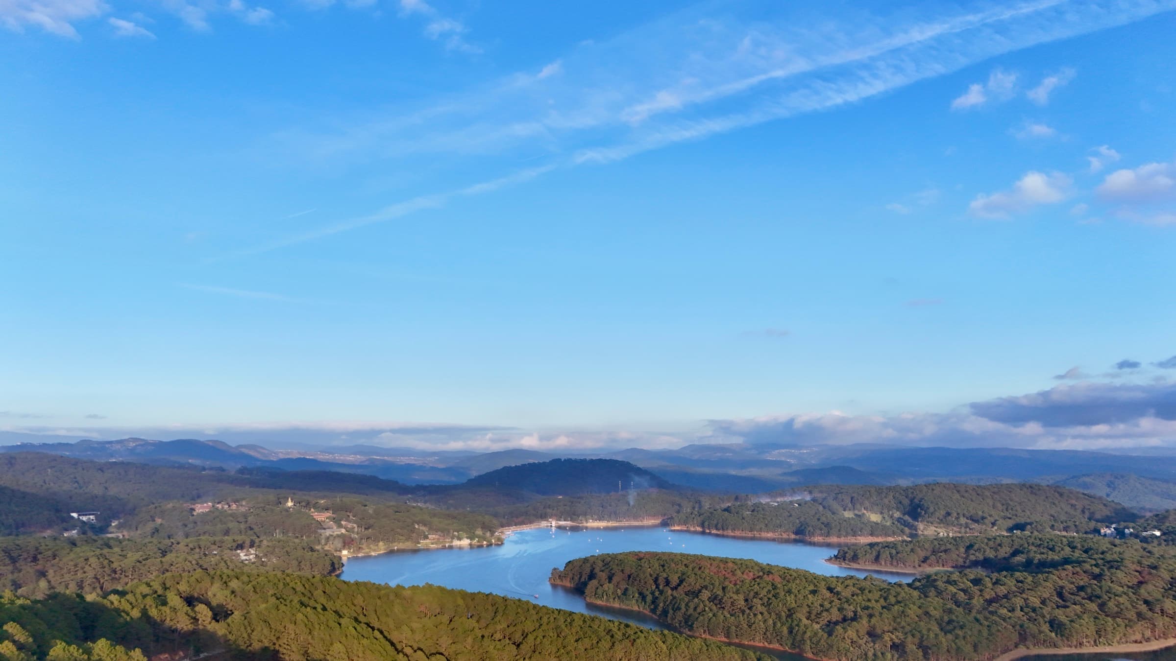 An aerial view across a blue lake and green hills in Vietnam