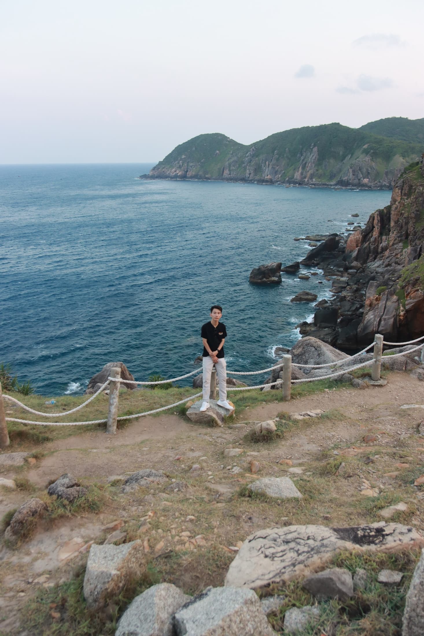Dong Pham standing on a rocky coast beside the sea