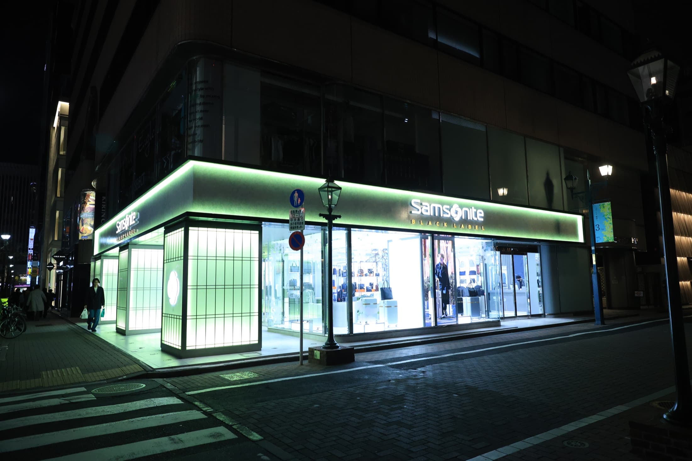 A green-lit storefront glowing on a dark Japanese street