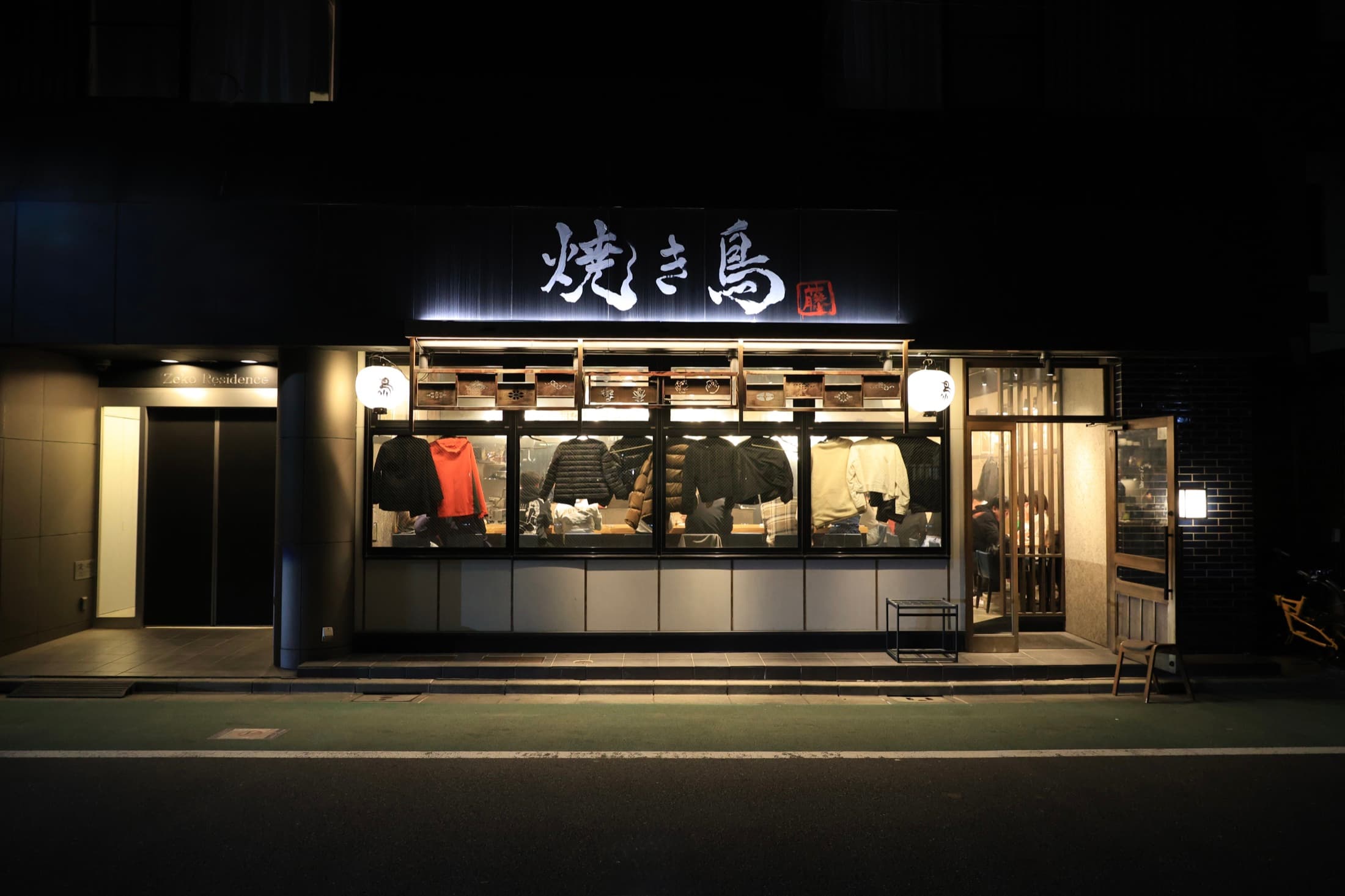 A warmly lit yakitori restaurant on a dark street in Japan